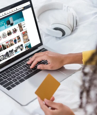 cropped image of woman holding credit card and using laptop with amazon  on screen